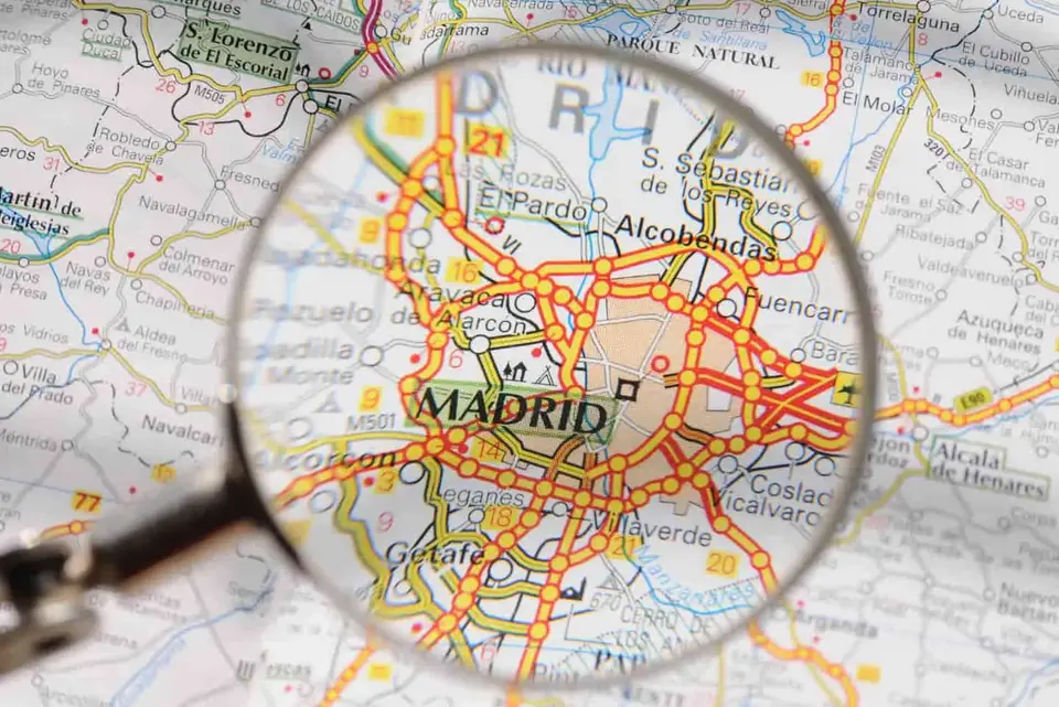 Lupa sobre un mapa de la Comunidad de Madrid, símbolo de la valoración de inmuebles y la tasación de viviendas en Madrid